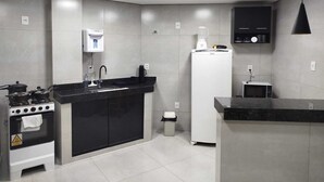 A modern kitchen with a stove, sink, refrigerator, and a coffee machine. - Central apartment, 1st floor, with air conditioning, garage, smart TV. (Montes Claros)