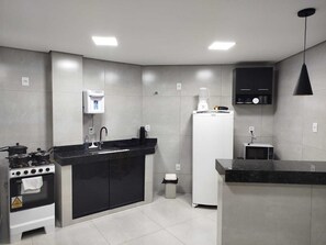 A modern kitchen with a stove, sink, refrigerator, and a coffee machine. - Central apartment, 1st floor, with air conditioning, garage, smart TV. (Montes Claros)