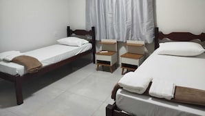 A room with two single beds, a small bedside table with a lamp, and an air conditioning unit on the wall. - Central apartment, 1st floor, with air conditioning, garage, smart TV. (Montes Claros)