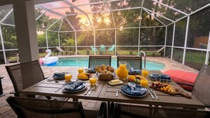 Ett utomhusområde med plats för att äta, med utsikt över en swimmingpool och träd.