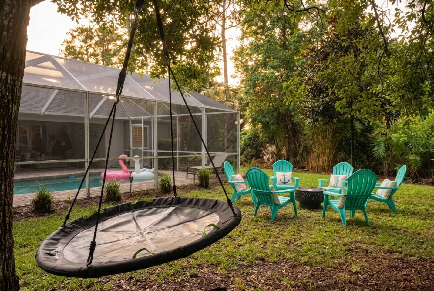 Ein Garten mit Trampolin, grünen Adirondack-Stühlen, Schwimmbecken und einer überdachten Terrasse.