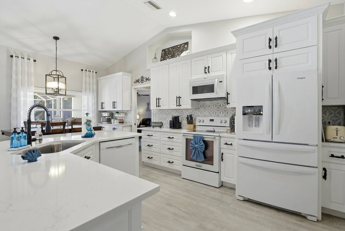 A modern kitchen with white cabinetry, a central island, and stainless steel appliances.