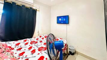 Una habitación con una cama, un televisor de pared, un ventilador de techo y un equipo de aire acondicionado.