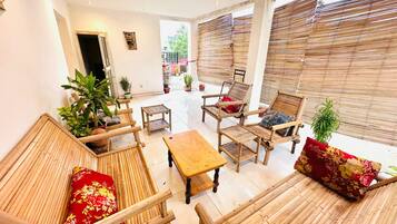 A room with bamboo furniture, including sofas and a table, and potted plants.