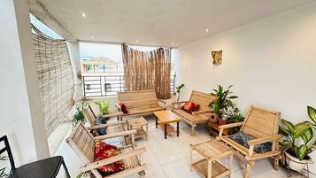 Amplia habitación con balcón, muebles de madera y plantas en macetas.