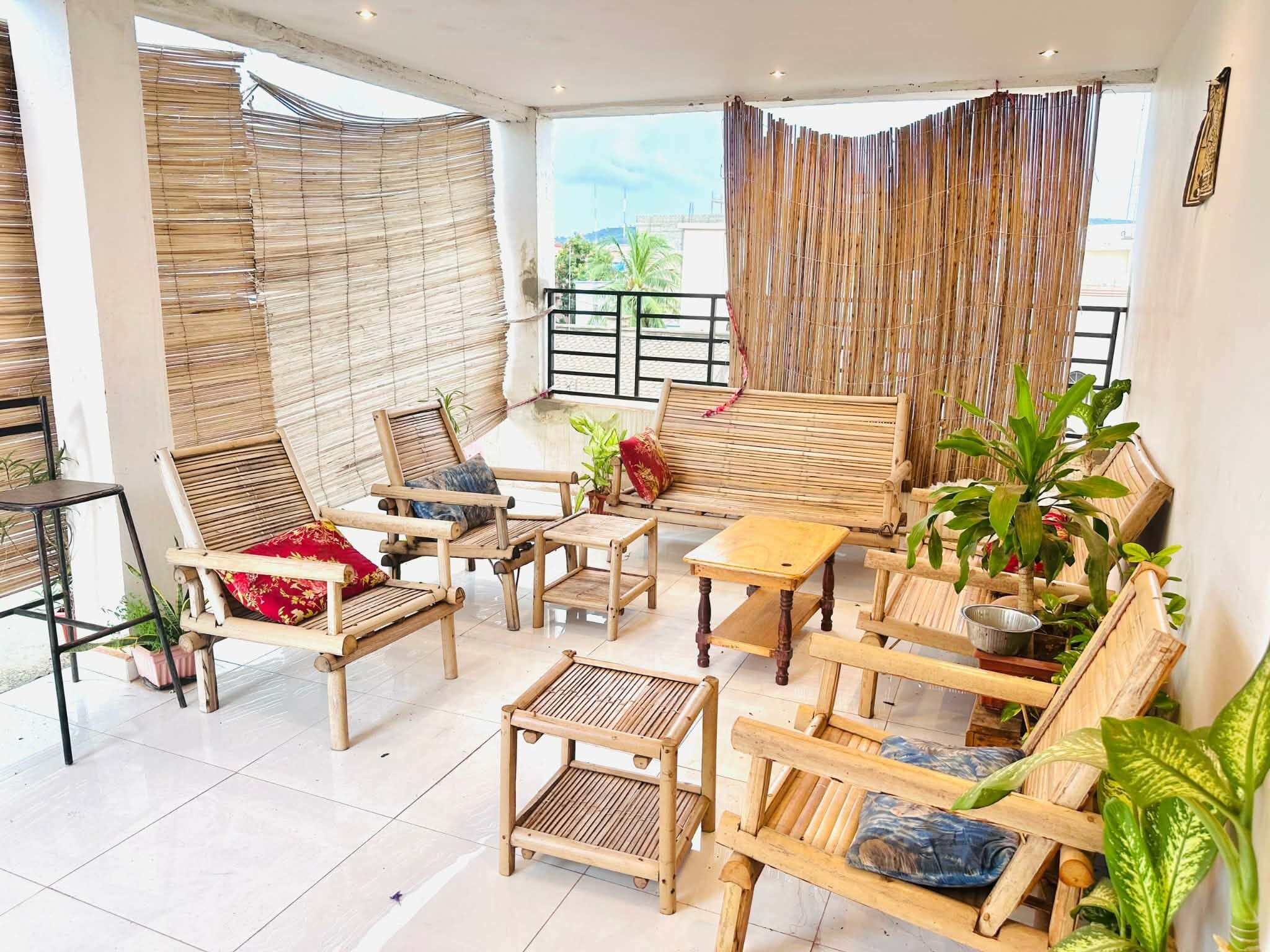 Un balcón amplio con mobiliario de bambú, incluyendo sillas y una mesa, y vistas del entorno.