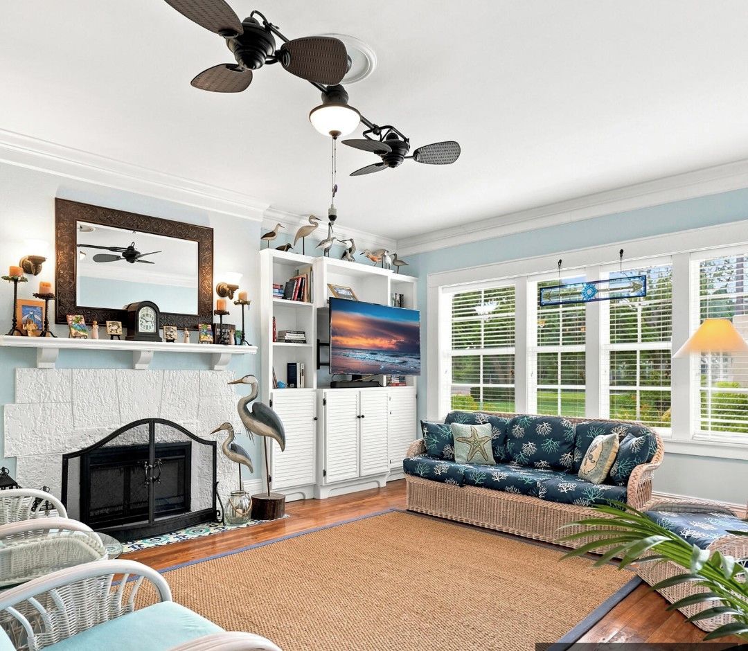 A living room with a fireplace, ceiling fans, a sofa, and a television.
