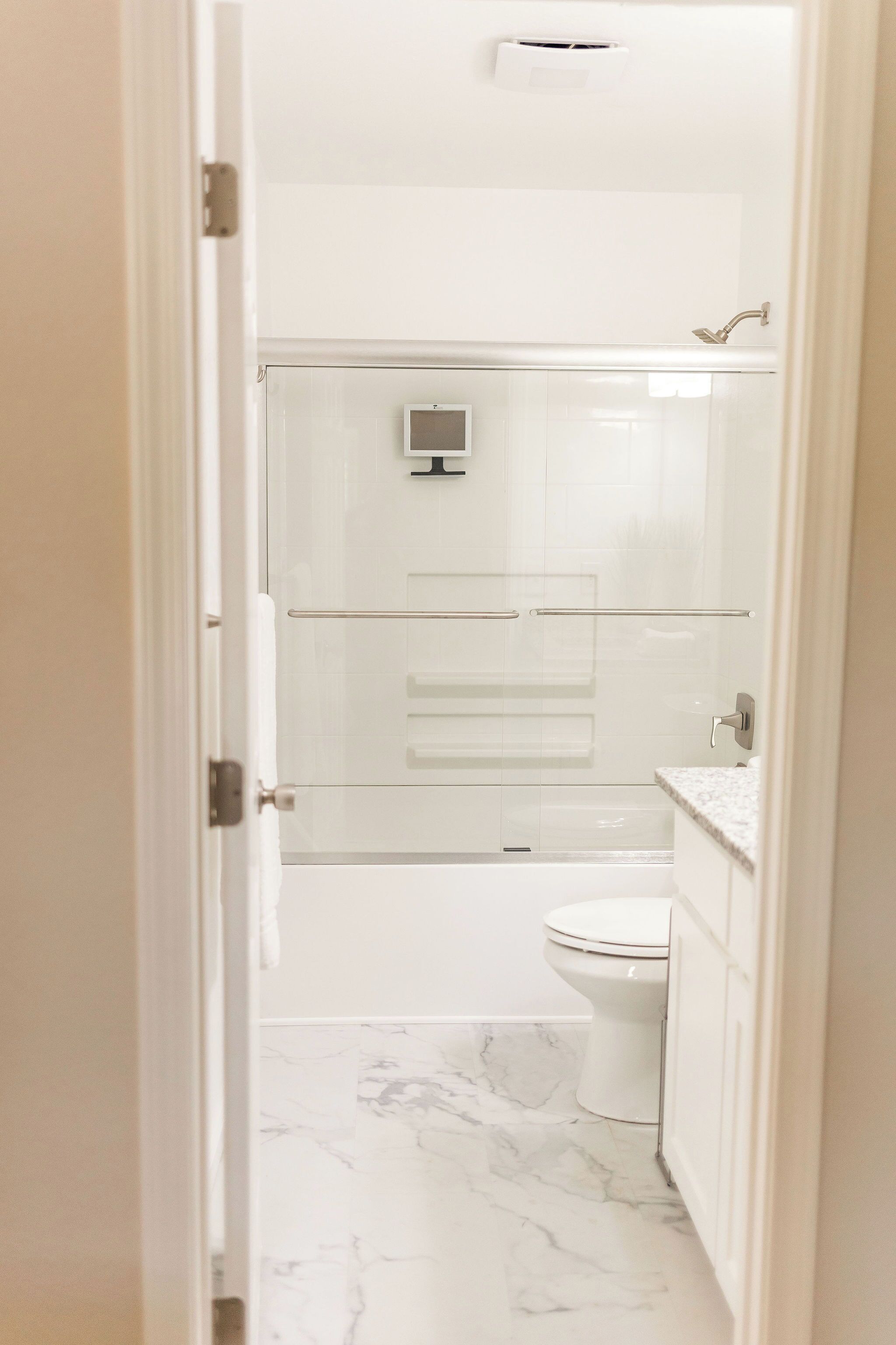 Ein Badezimmer mit Toilette, Dusche und einem durch eine Glaswand abgetrennten Waschtisch.