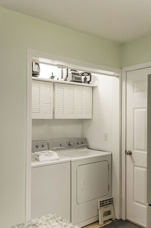 A laundry room with a washing machine, dryer, and a small shelf above the dryer. - Ride-Out-the-Door to Slaughter Pen- Hot Tub, Sauna & Gym 10 min to OZ Bike Park (Bentonville)