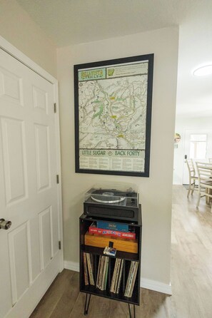 A framed map of Bellavista Trails on a wall, a record player on a shelf, and a door to the left. - Ride-Out-the-Door to Slaughter Pen- Hot Tub, Sauna & Gym 10 min to OZ Bike Park (Bentonville)