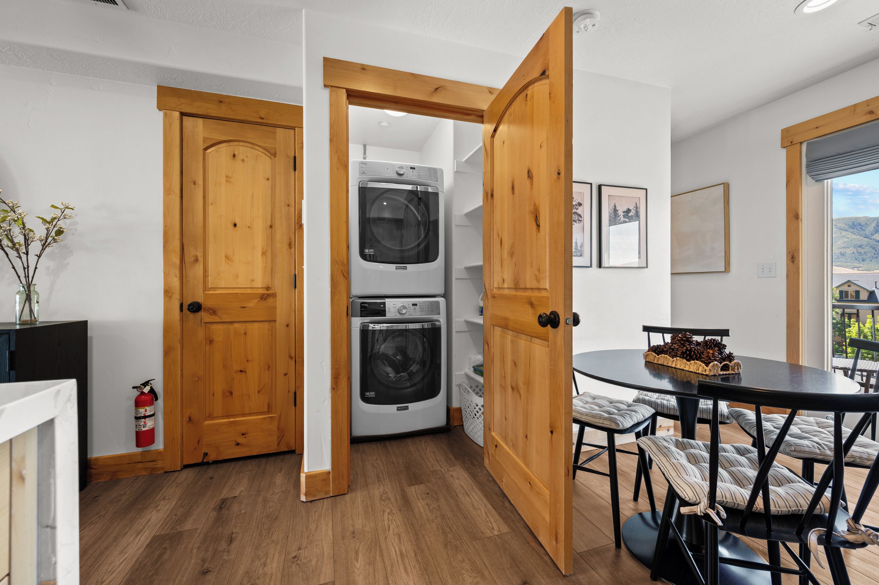 Une cuisine moderne avec des portes en bois, un lave-linge et un sèche-linge intégrés, et un coin repas avec une table ronde et des chaises.