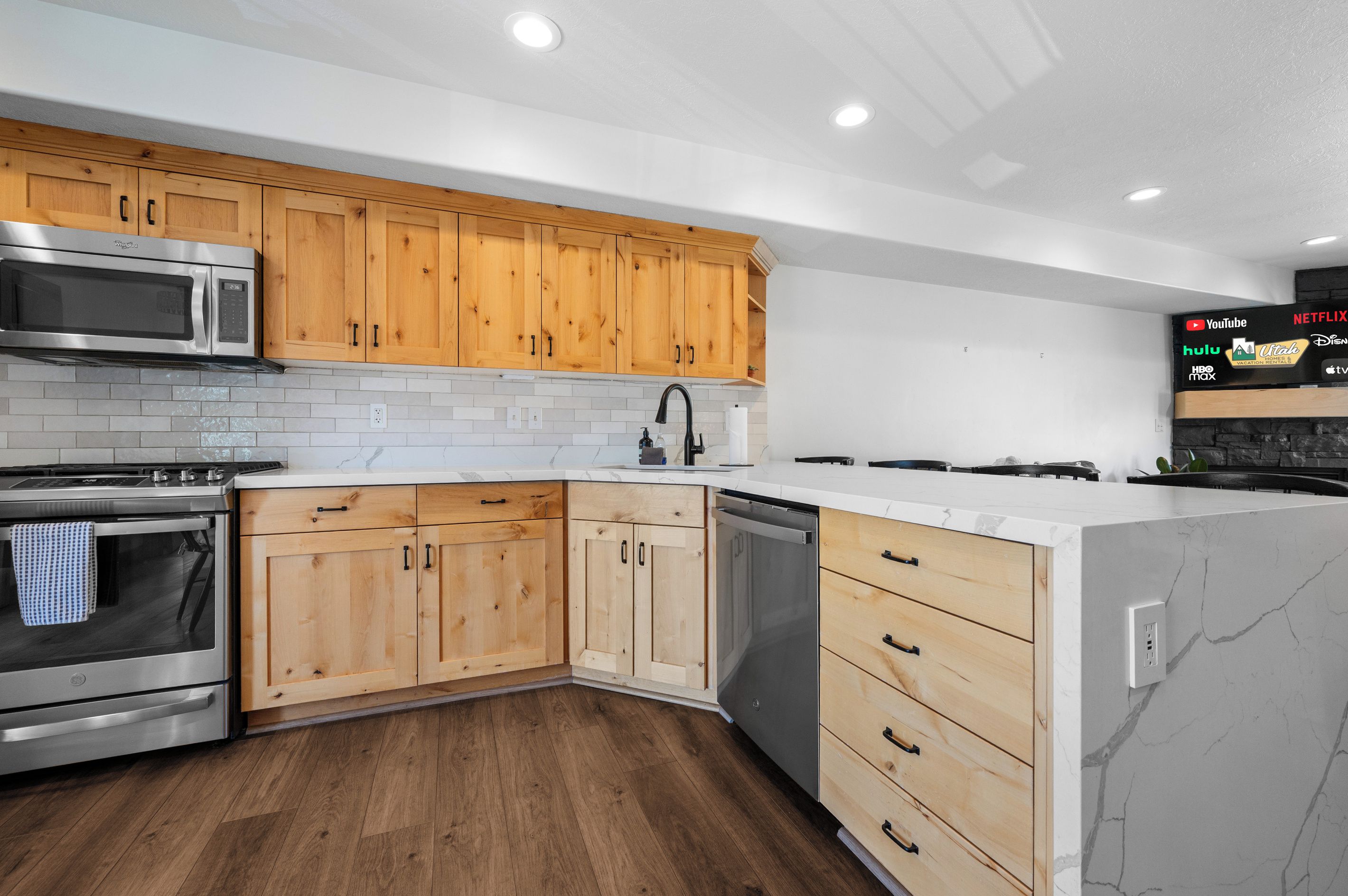 Una cocina moderna con armarios de madera, electrodomésticos de acero inoxidable y una encimera de mármol.