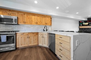 Una cocina moderna con armarios de madera, electrodomésticos de acero inoxidable y una encimera de mármol.