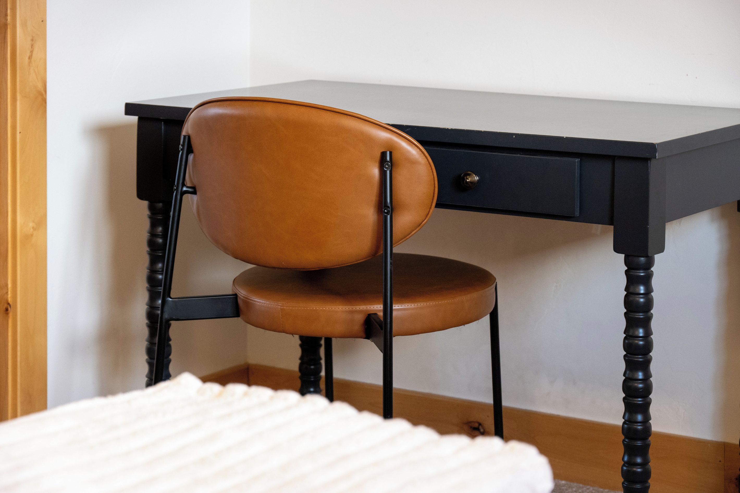 Une chaise dotée d’un siège et d’un dossier en cuir, placée devant un bureau muni d’un tiroir.
