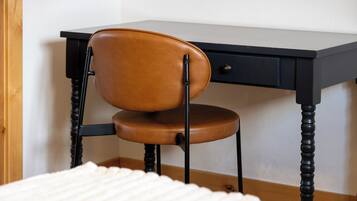 Una silla con asiento y respaldo de cuero, ubicada frente a un escritorio con cajón.