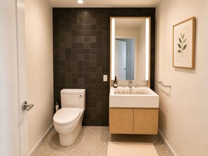 A modern bathroom with a toilet, sink, and mirror. - FiDi High-Rise · Skyline Views · Luxury Amenities (New York)