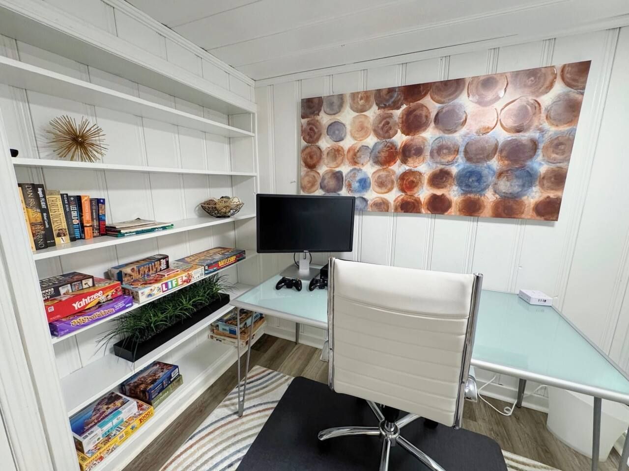 A study room with a desk, chair, bookshelf, and a wall with a circular pattern.