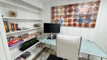 A study room with a desk, chair, bookshelf, and a wall with a circular pattern.