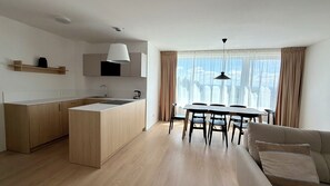 A modern kitchen with a central island, a dining area with a table and chairs, and a sofa in a living space. - Phenomenal 2-bedroom apartment in charming Gerlachov awaits you (Gerlachov)