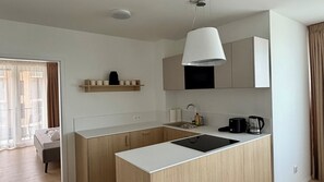 A modern kitchen with a central island, a hanging light fixture, and a built-in oven. - Phenomenal 2-bedroom apartment in charming Gerlachov awaits you (Gerlachov)