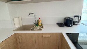 Eine Küche mit Spüle, Wasserkocher, Toaster und einer Flasche Geschirrspülmittel.