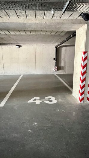 Eine Parkgarage mit Betonwänden, einer Metalldecke und einer roten und weißen Streifenbarriere.