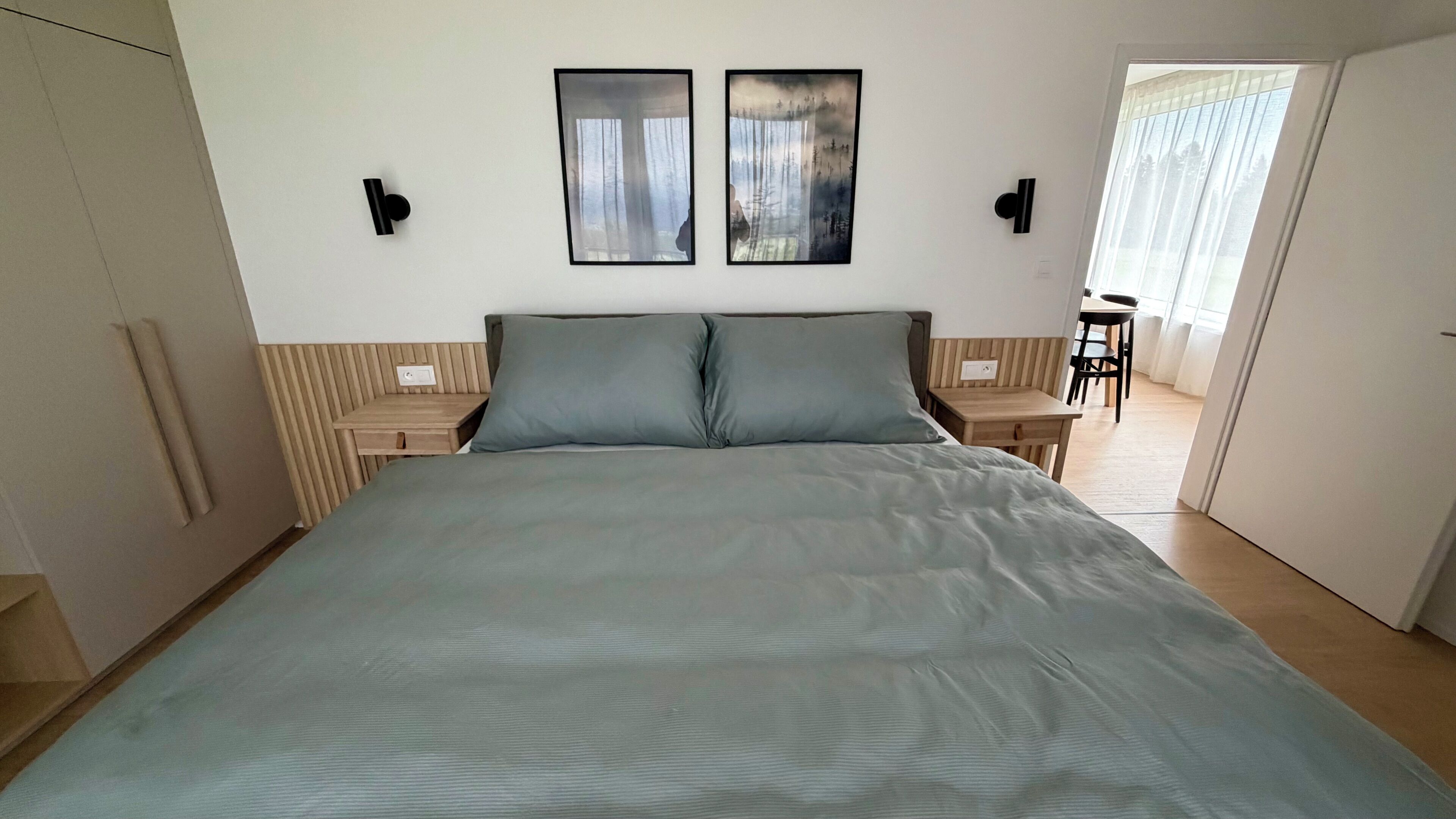 Une chambre à coucher comprenant un lit, deux tables de chevet, une armoire et donnant sur un coin repas.