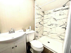 A bathroom with a white sink, toilet, and shower area. - Tiny but Mighty Home - 7 mins from DT (Jacksonville)