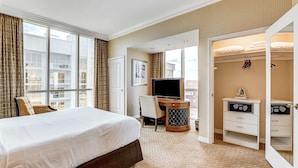 Una habitación de hotel con una cama grande, un escritorio con televisor y un vestidor.