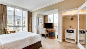 Ein Hotelzimmer mit einem großen Bett, einem Schreibtisch mit Fernseher und einem begehbaren Kleiderschrank.