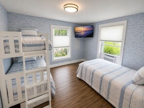 A bedroom with bunk beds, a flat-screen TV, and a window with blinds.