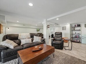 A modern living room with a leather sofa, a wooden coffee table, and a leather armchair. - Cedar Lake Social - 3BR/3BA Waterfront Retreat + Private Dock & Prime Lake Views (Cedar Lake)