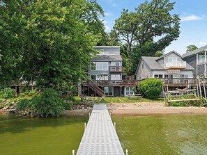 A waterfront property with a dock leading to a house with multiple levels and balconies. - Cedar Lake Social - 3BR/3BA Waterfront Retreat + Private Dock & Prime Lake Views (Cedar Lake)