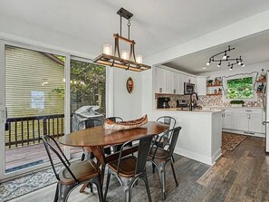 A dining area with a wooden table and chairs, a chandelier, and a view of the outdoors. - Cedar Lake Social - 3BR/3BA Waterfront Retreat + Private Dock & Prime Lake Views (Cedar Lake)