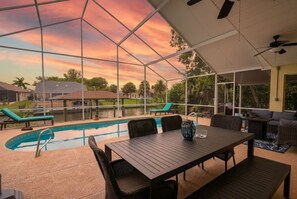 Eine Terrasse im Freien mit Pool, Sitzgelegenheiten und Blick auf den Sonnenuntergang.