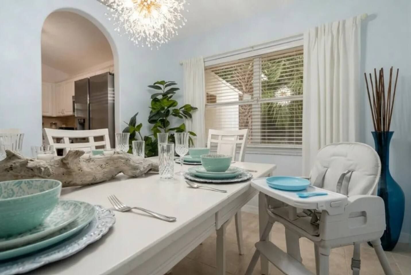 Un coin repas avec une table blanche dressée pour quatre personnes, comprenant des assiettes, des verres et des couverts.