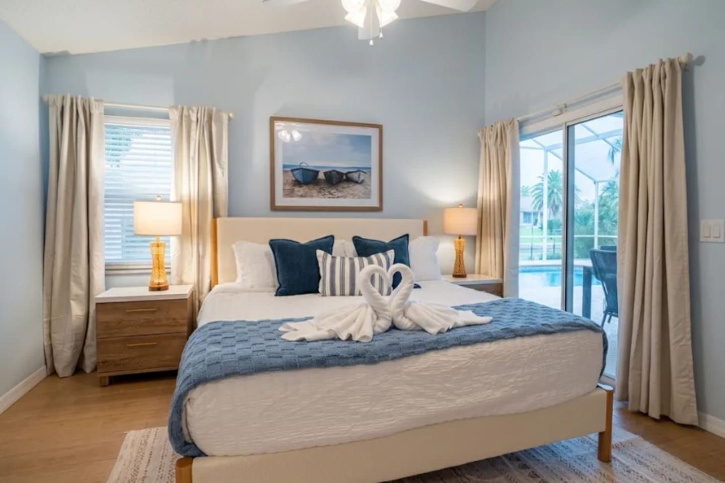 Une chambre d’hôtel avec un lit, deux tables de chevet, une fenêtre avec des rideaux, un tableau encadré au mur et une vue sur l’extérieur.