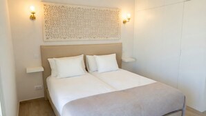 Quarto com cama, duas mesas de cabeceira e um painel decorativo na parede.