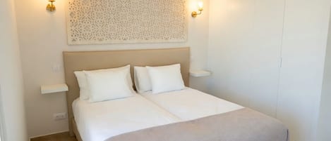 Un dormitorio con una cama, dos mesitas de noche y un panel decorativo en la pared.