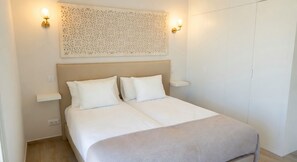A bedroom with a bed, two bedside tables, and a decorative wall panel. - Vrbo Property (Silves)