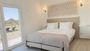 Quarto com cama, janela e vista para área externa.