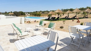 Área da piscina com espreguiçadeiras e guarda-sóis, uma piscina e vista para a paisagem.