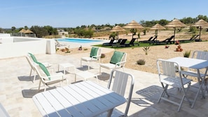 A poolside area with lounge chairs and umbrellas, a pool, and a view of the landscape. - Vrbo Property (Silves)