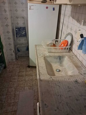 Eine Küche mit Spüle, Kühlschrank und einer Leiter.