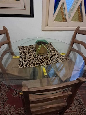 Ein runder Glastisch mit einer Tischmatte mit Leopardenmuster, einer kleinen Pflanze und einem gelben Gegenstand darauf.