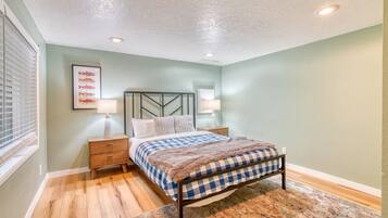 Une chambre à coucher avec un lit, des tables de chevet, une lampe fixée au mur, un tableau représentant un poisson, et un tapis à motifs.
