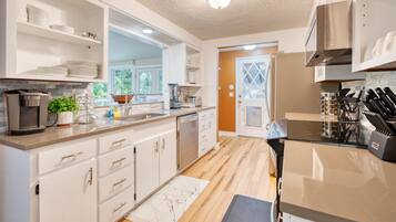 A modern kitchen with white cabinetry, a built-in oven, and a coffee machine.