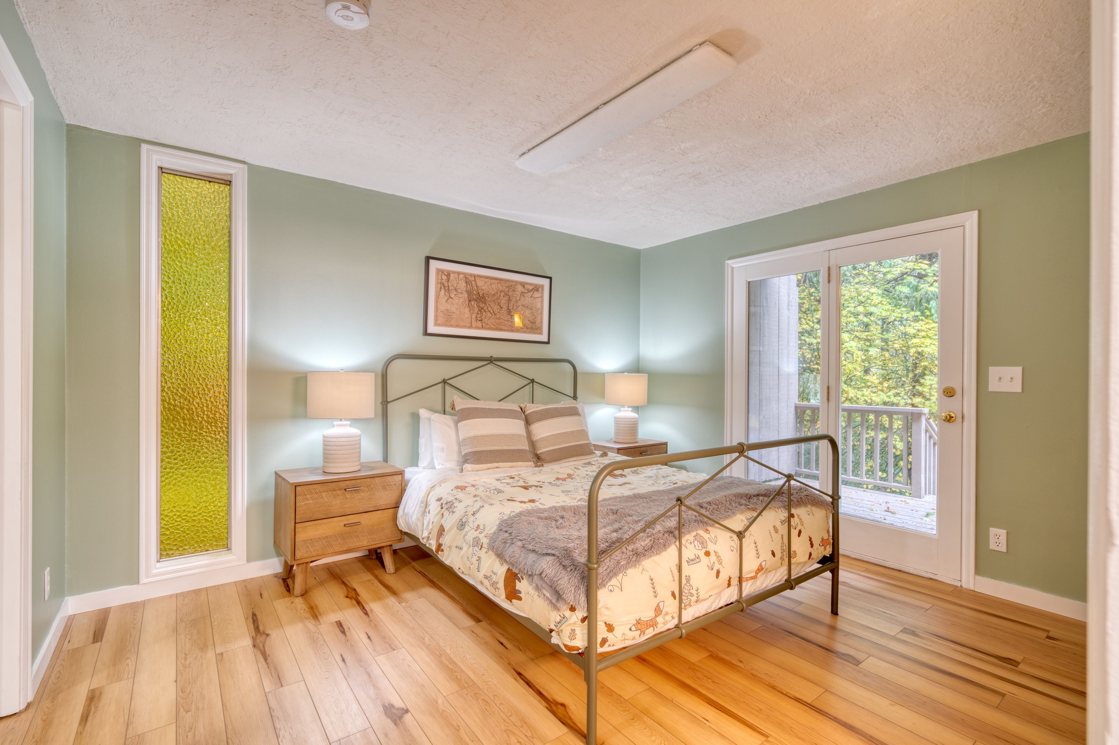 A bedroom with a bed, bedside tables, a headboard, a window, and a door leading to a balcony.