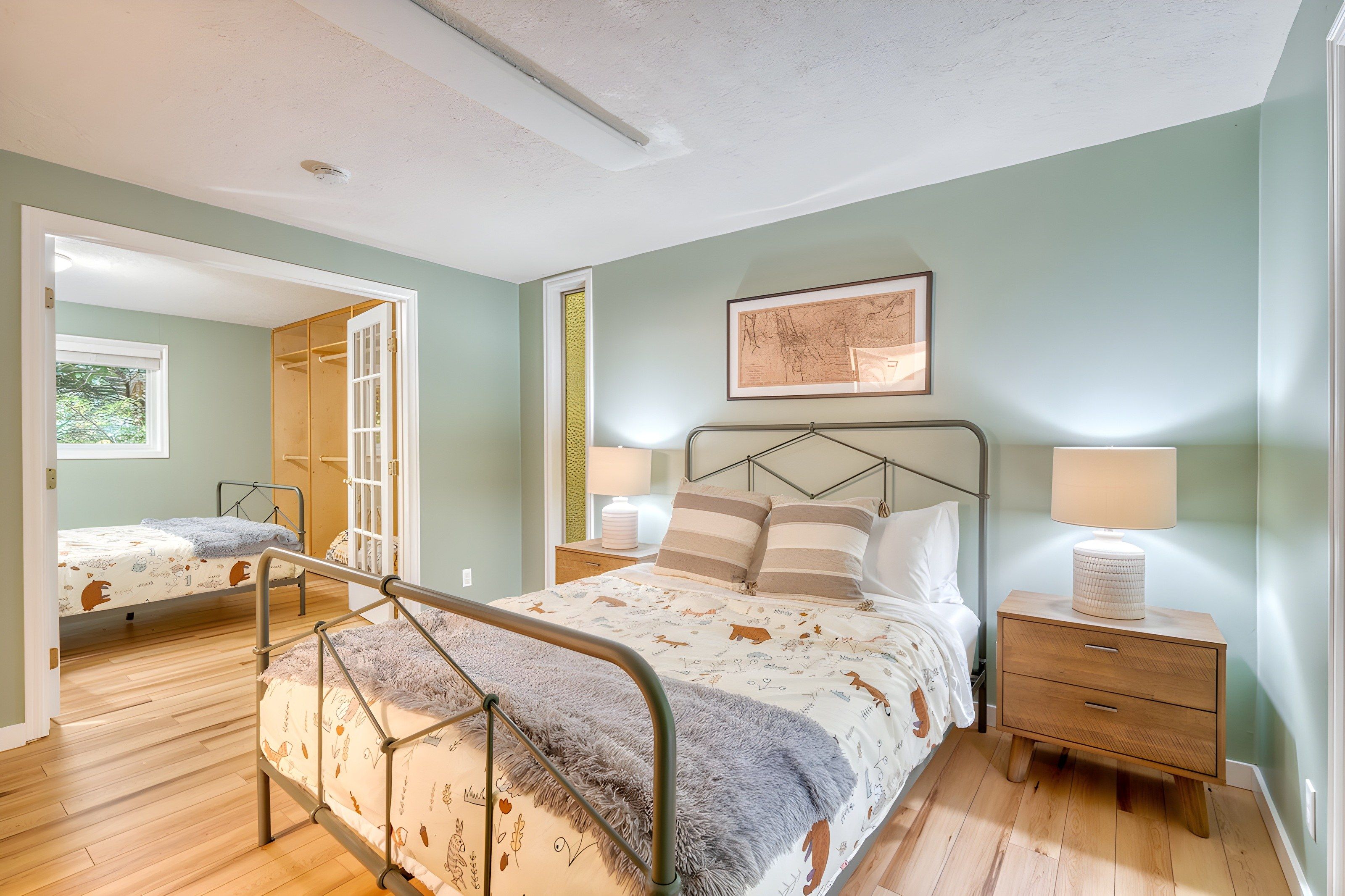 A bedroom with a bed, bedside tables, a mirror, and a framed picture on the wall.