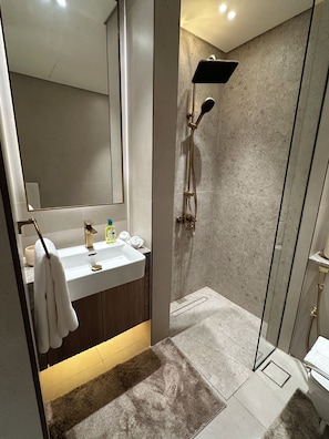 A modern bathroom with a glass-enclosed shower, a sink with a mirror, and a towel rack. - Binghatti Apex (Dubai)
